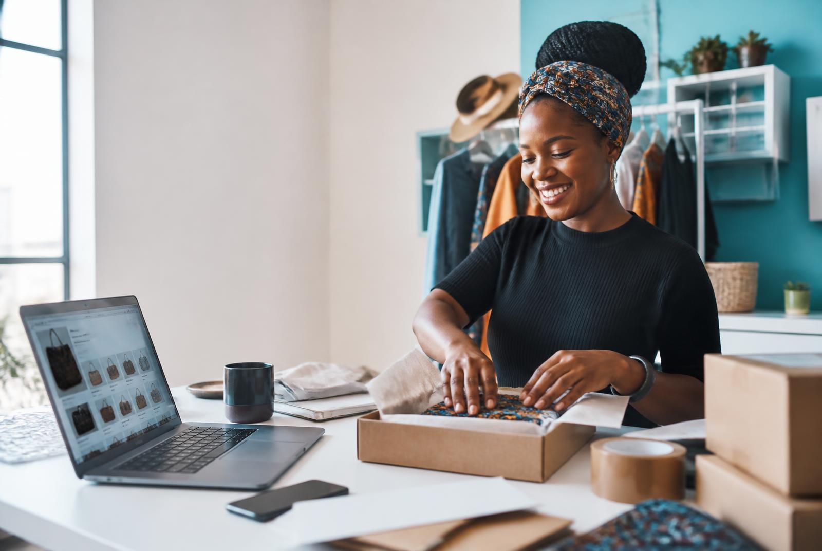 Small business owner packing an online order beside her ecommerce website
